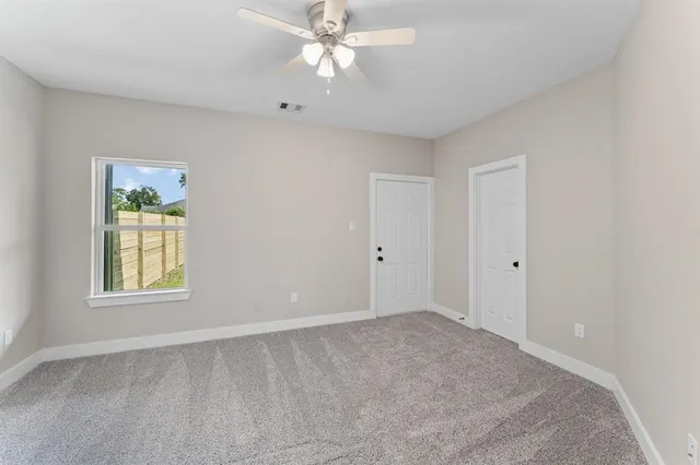 an empty room with windows and fan