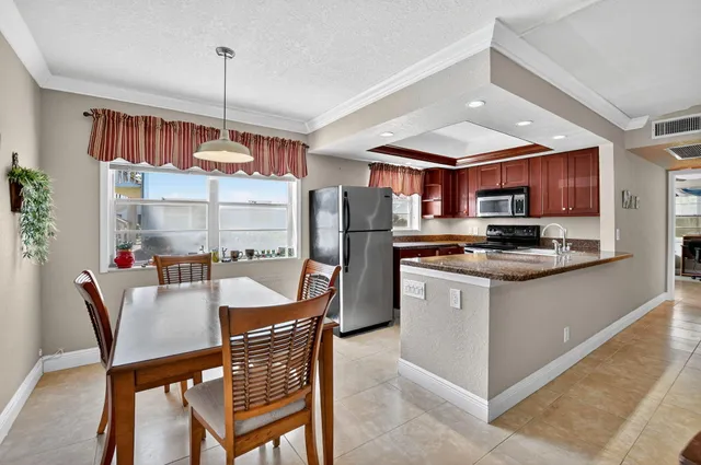 a kitchen with stainless steel appliances granite countertop a stove refrigerator a dining table and chairs with the wooden floor