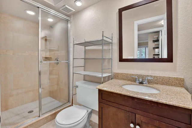 a bathroom with a granite countertop sink toilet a mirror and shower