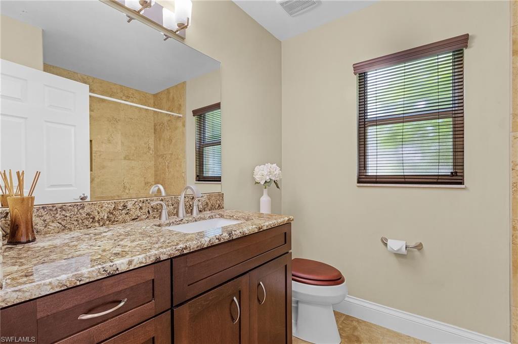128 Plantation Circle Naples, FL 34104 - Photo 19 of 27 a bathroom with a granite countertop sink toilet and mirror