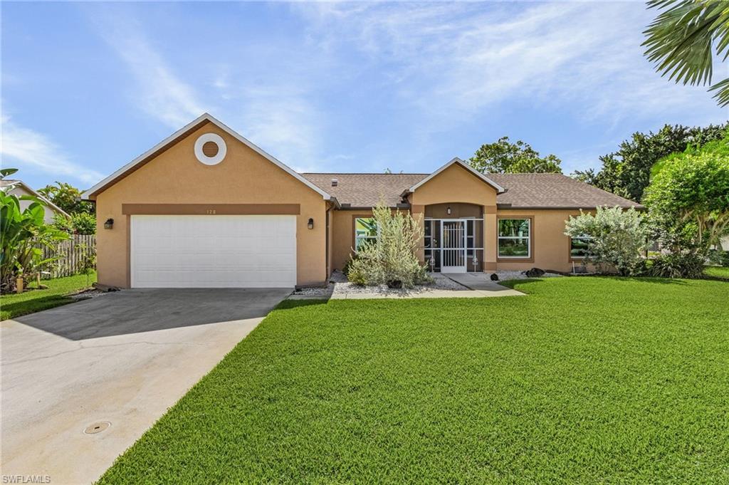 128 Plantation Circle Naples, FL 34104 - Photo 26 of 27 a front view of a house with a yard and garage