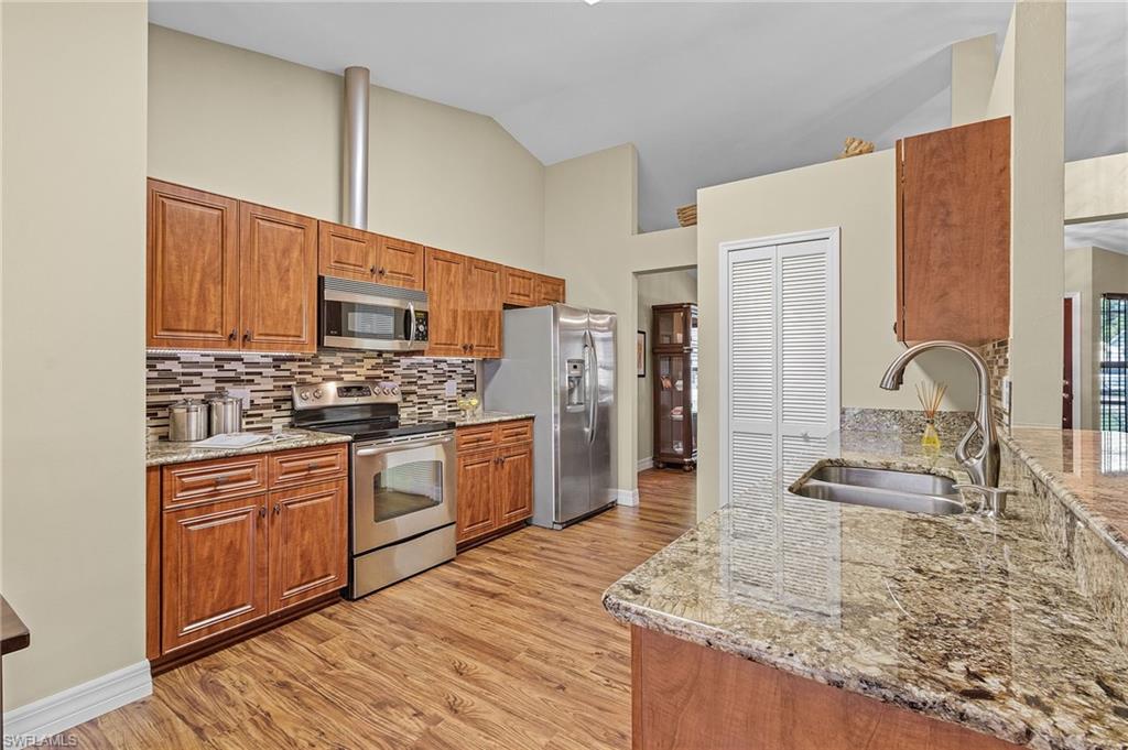 128 Plantation Circle Naples, FL 34104 - Photo 7 of 27 a kitchen with stainless steel appliances kitchen island granite countertop a stove a sink and a microwave