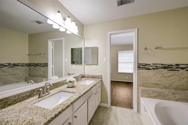 a bathroom with a granite countertop double vanity sink and mirror with shower