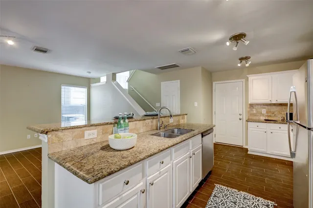a kitchen with a sink dishwasher and white cabinets with wooden floor
