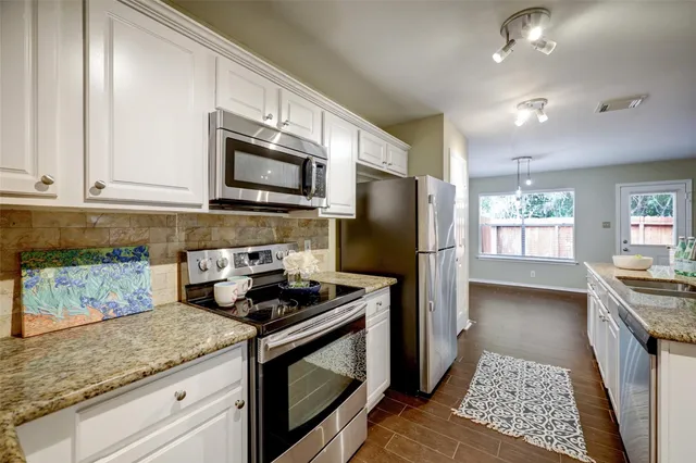 a kitchen with granite countertop stainless steel appliances a stove microwave and refrigerator