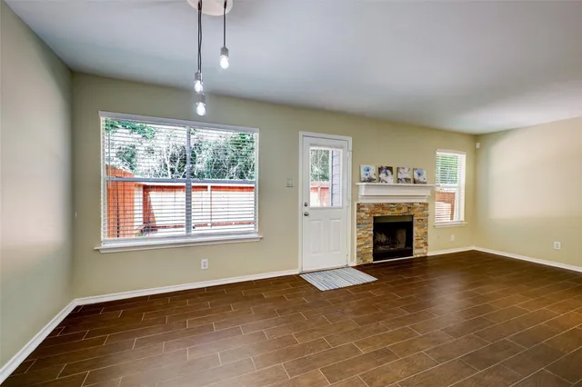 an empty room with wooden floor fireplace and windows