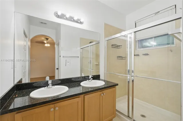 a bathroom with a granite countertop sink mirror and a shower