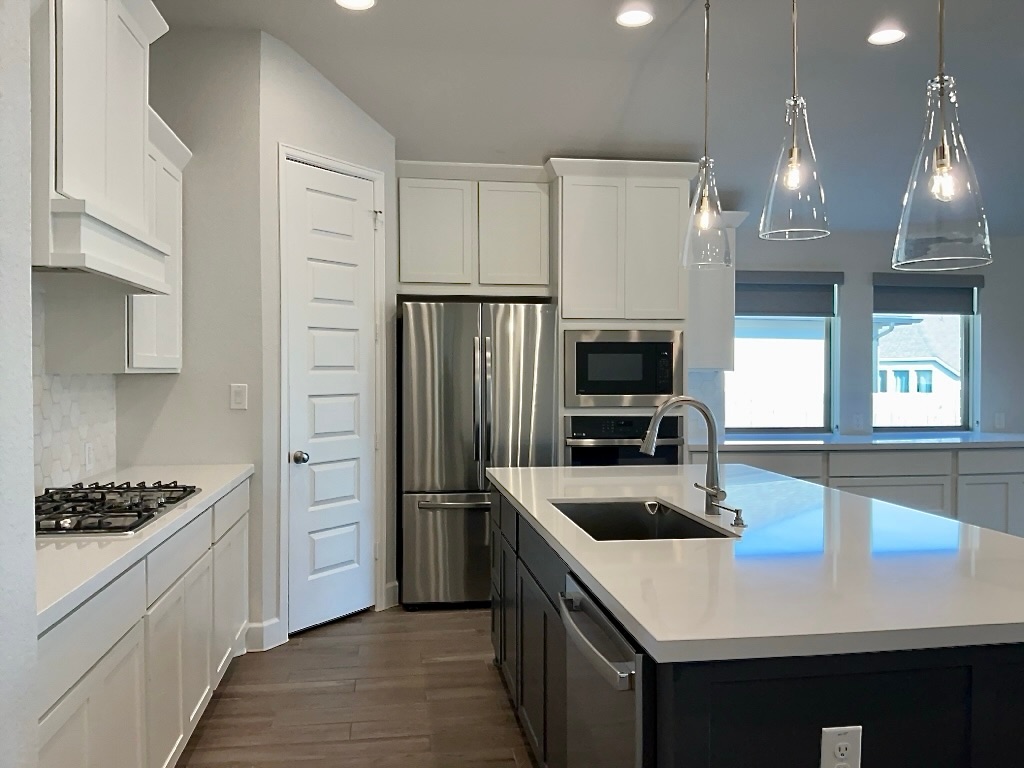1636 Laverne Mitchell Street Leander, TX 78641 - Photo 7 of 20 Kitchen with stainless steel appliances, white cabinetry, decorative light fixtures, dark wood-type flooring, and dark cabinetry
