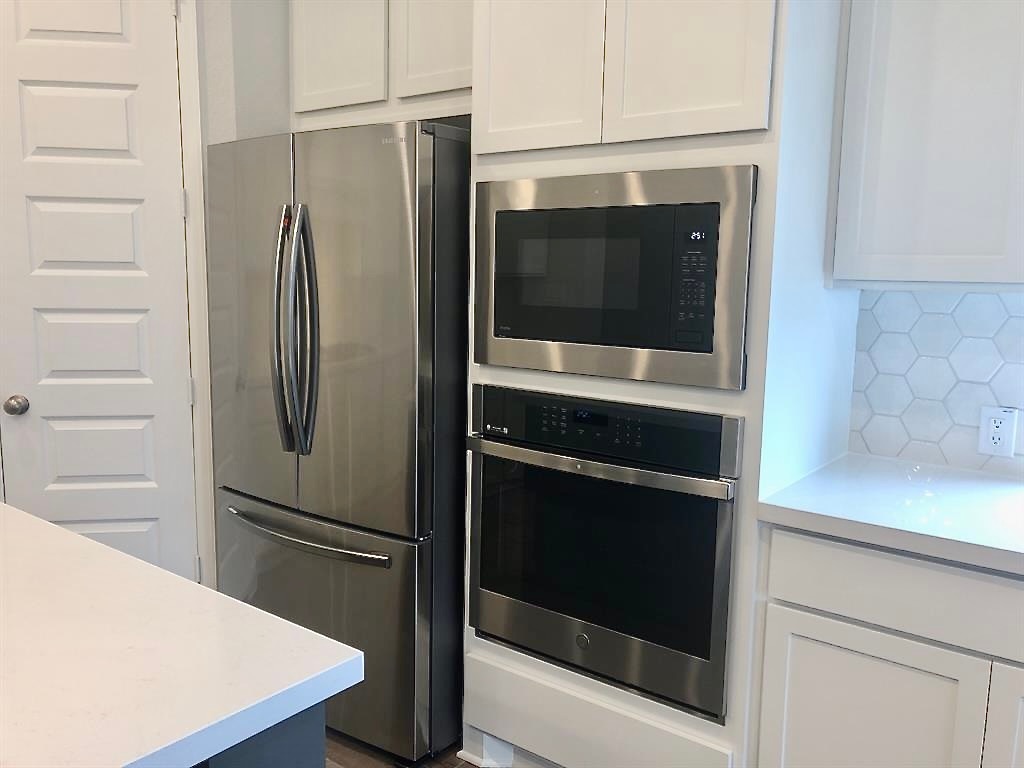 1636 Laverne Mitchell Street Leander, TX 78641 - Photo 8 of 20 Kitchen with light countertops, stainless steel appliances, and white cabinets