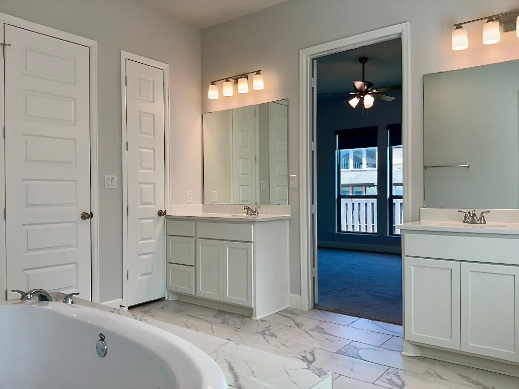1636 Laverne Mitchell Street Leander, TX 78641 - Photo 10 of 20 Primary bathroom with light marble finish floors, a large soaking tub, two vanities, and step in shower and two walk-in closets