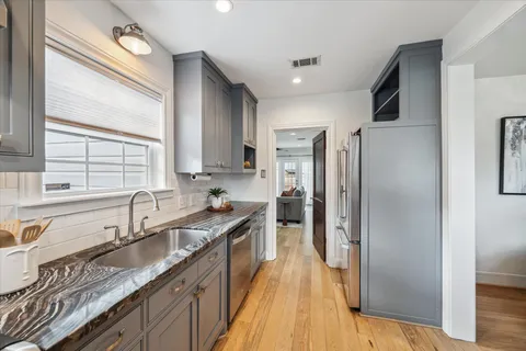 a kitchen that has a sink a stove and cabinets