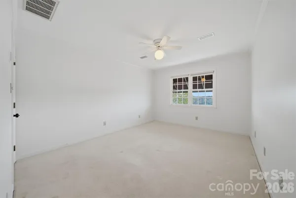 an empty room with windows and ceiling fan