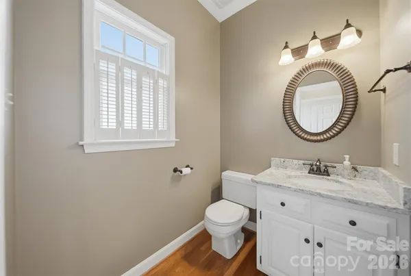a bathroom with a toilet a sink a mirror and a window