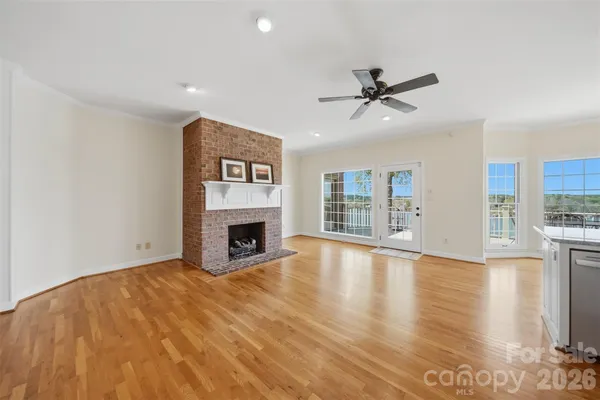 a view of a livingroom with a fireplace a ceiling fan and windows