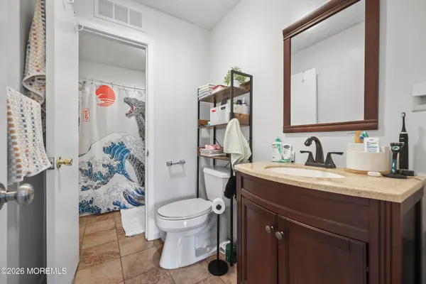 a bathroom with a granite countertop sink vanity mirror and toilet