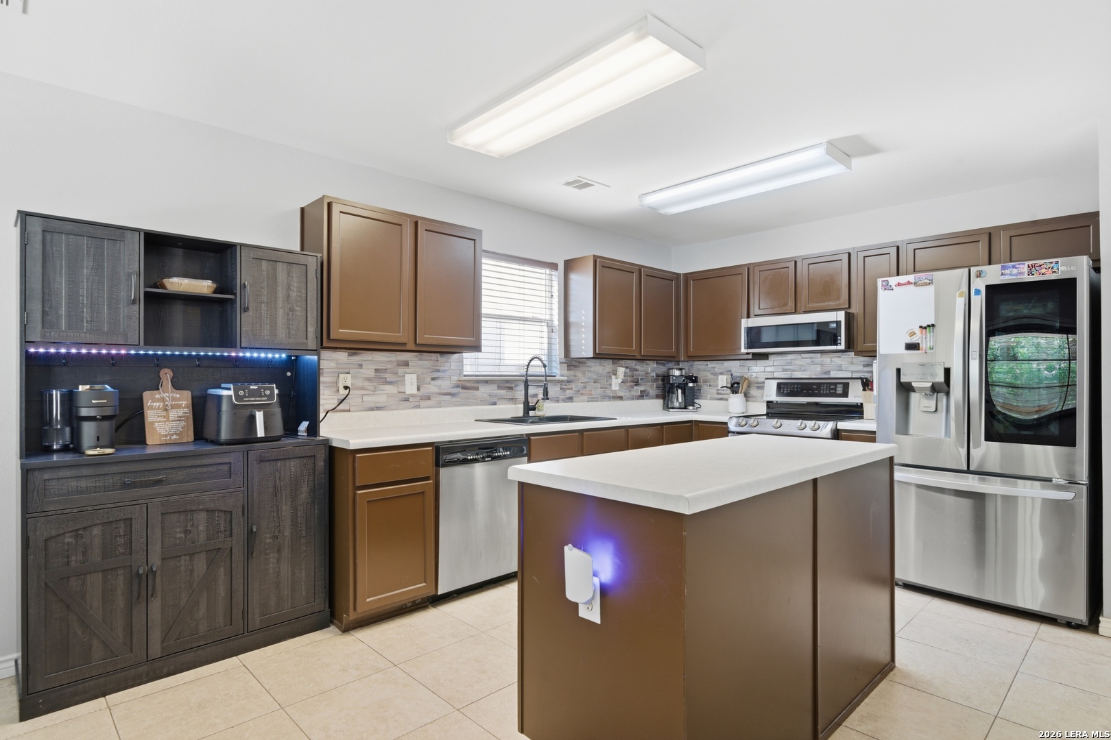 11622 Shotgun Way Helotes, TX 78023 - Photo 11 of 35 a kitchen with stainless steel appliances granite countertop a stove top oven a sink dishwasher and a refrigerator with wooden cabinets