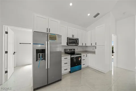 a large white kitchen with a large window and stainless steel appliances