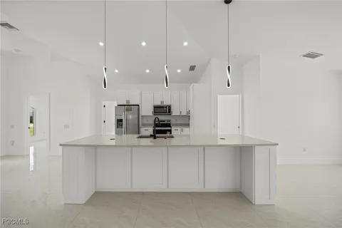 a kitchen with stainless steel appliances a sink a stove a refrigerator a center island and cabinets