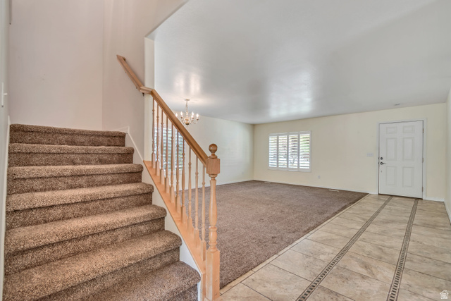 546 Wheatridge Road Tooele, UT 84074 - Photo 19 of 49 Entryway featuring tiled flooring with decorative inlays, a white paneled front door, and a carpeted staircase with a wood railing