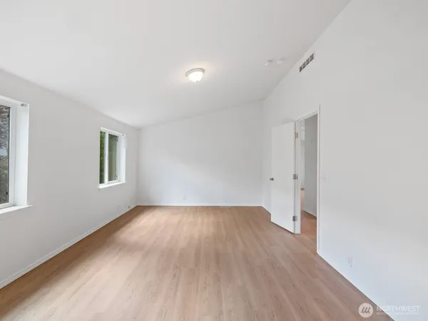 an empty room with wooden floor and windows