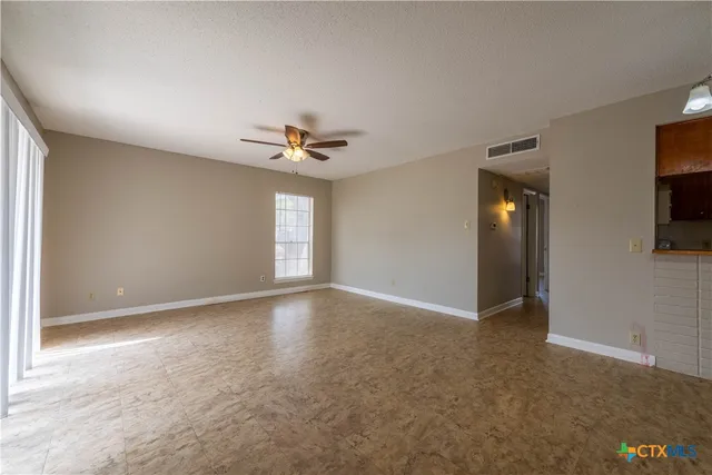 a view of an empty room with a bathroom and a window