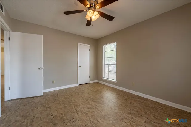 a view of an empty room with window and chandelier fan