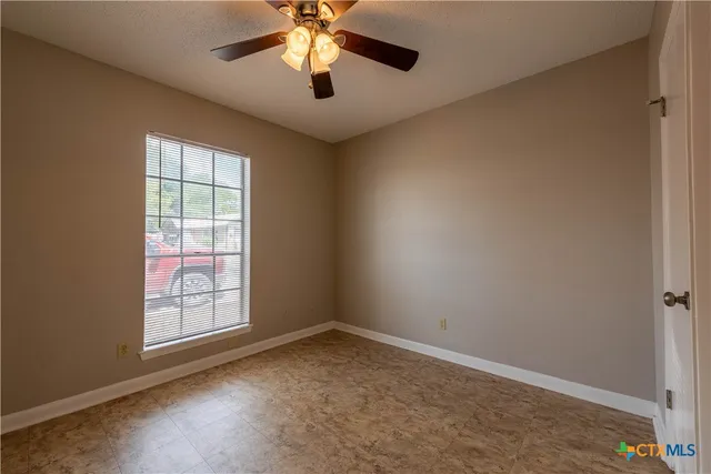 an empty room with a window and a fan