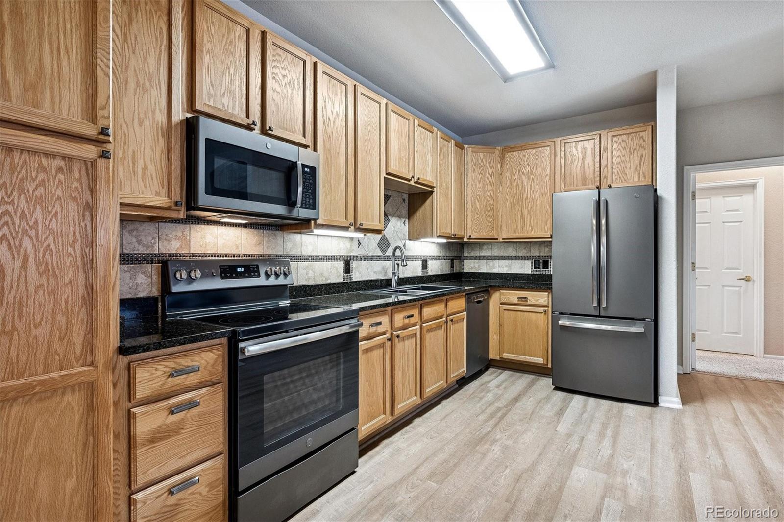 22960 East Roxbury Drive, Unit F Aurora, CO 80016 - Photo 8 of 43 a kitchen with granite countertop a refrigerator stove and microwave
