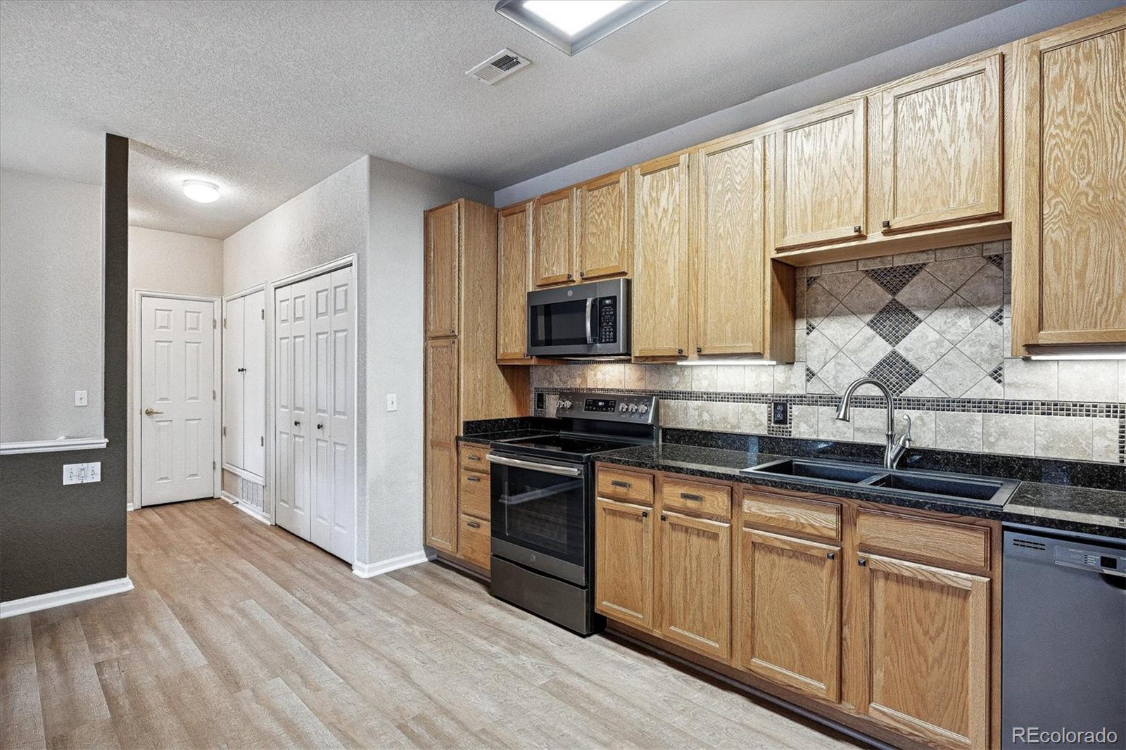 22960 East Roxbury Drive, Unit F Aurora, CO 80016 - Photo 10 of 43 a kitchen with stainless steel appliances granite countertop a stove a sink and a microwave