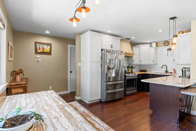 a kitchen with stainless steel appliances granite countertop a refrigerator a sink and a stove with wooden floor