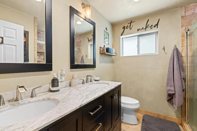a bathroom with a granite countertop sink toilet and mirror