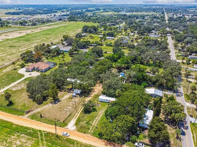 an aerial view of residential houses with outdoor space and trees