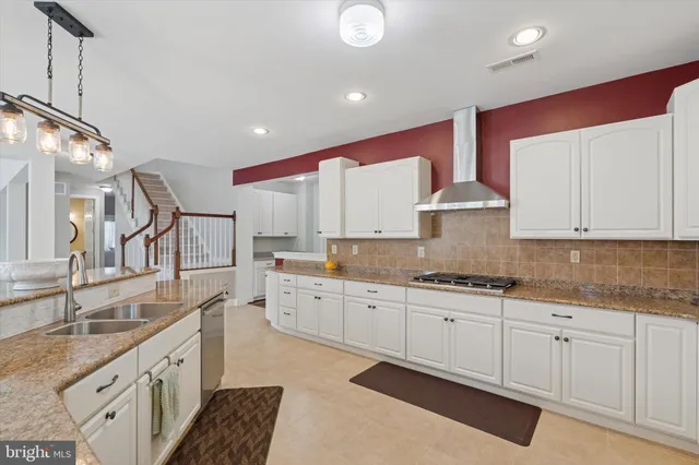 a kitchen with stainless steel appliances kitchen island granite countertop a dining table chairs refrigerator and microwave