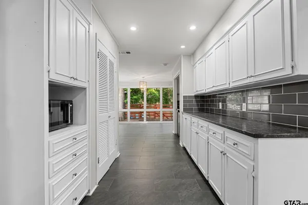 a kitchen with granite countertop white cabinets and window