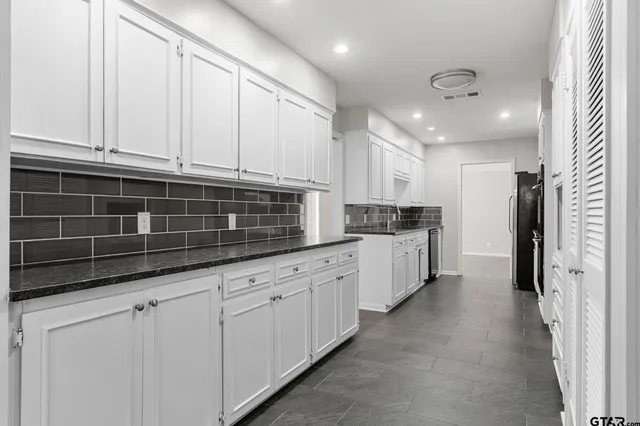 a kitchen with granite countertop white cabinets and stainless steel appliances