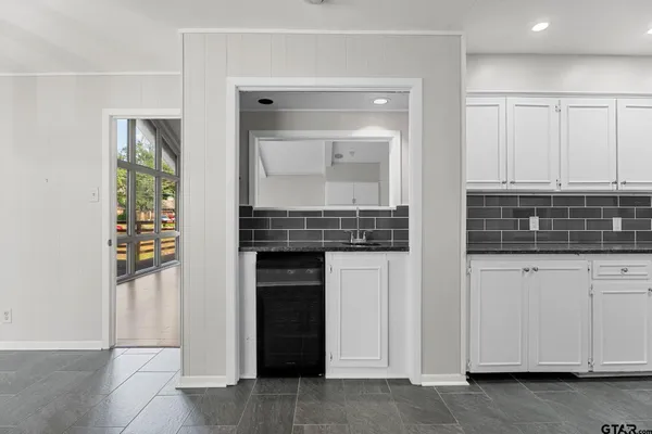 a view of kitchen with granite countertop white cabinets and sink