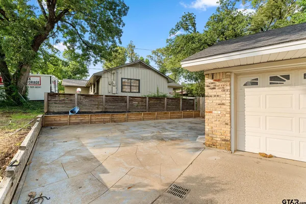 a backyard of a house with large trees and barbeque oven