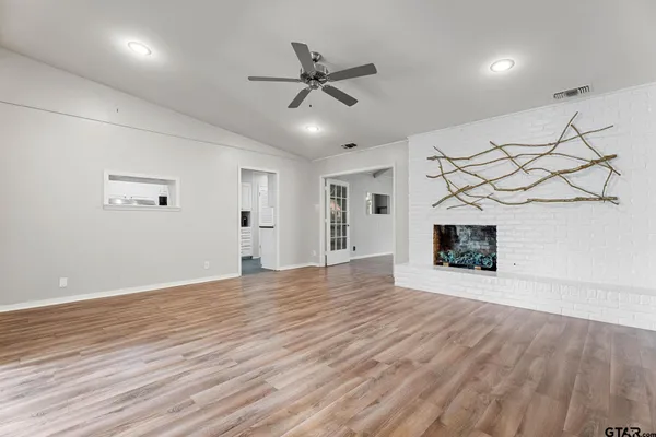 a view of an empty room with a fireplace and a ceiling fan