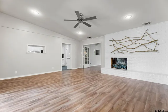 a view of an empty room with a fireplace and a ceiling fan