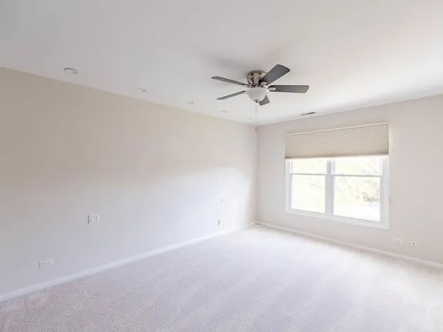 an empty room with a window and a ceiling fan