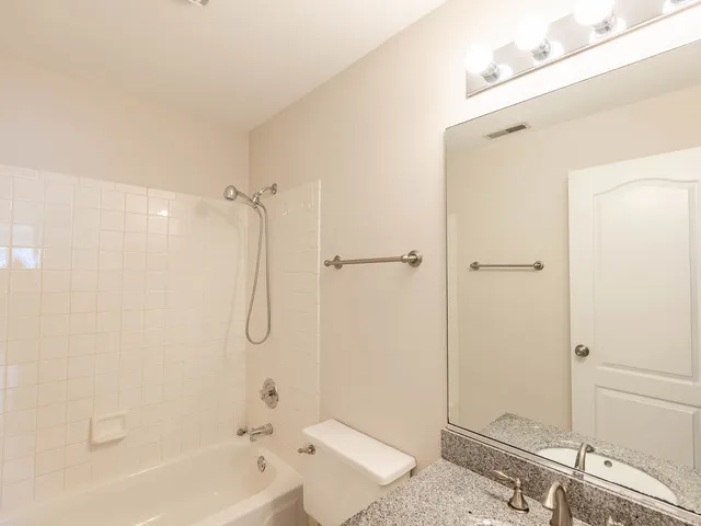 a bathroom with a granite countertop bathtub shower sink and toilet