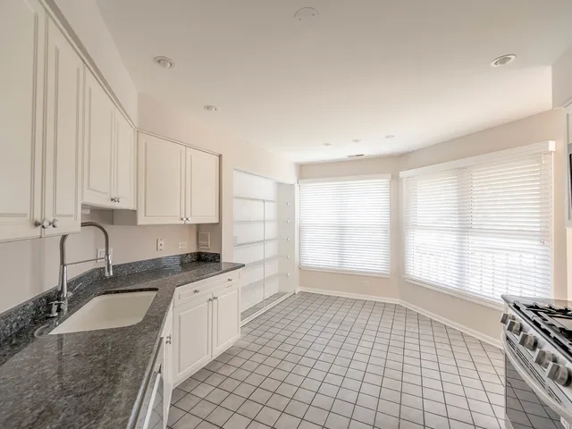 a large white kitchen with granite countertop a sink a granite counter tops and a stove