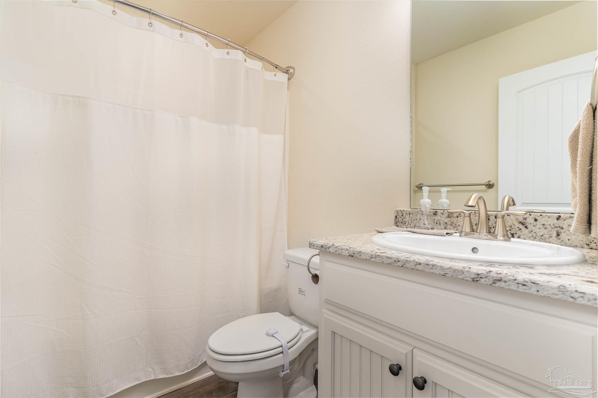 3315 Doyle Hawkins Road Navarre, FL 32566 - Photo 23 of 33 a bathroom with a granite countertop sink toilet and a mirror