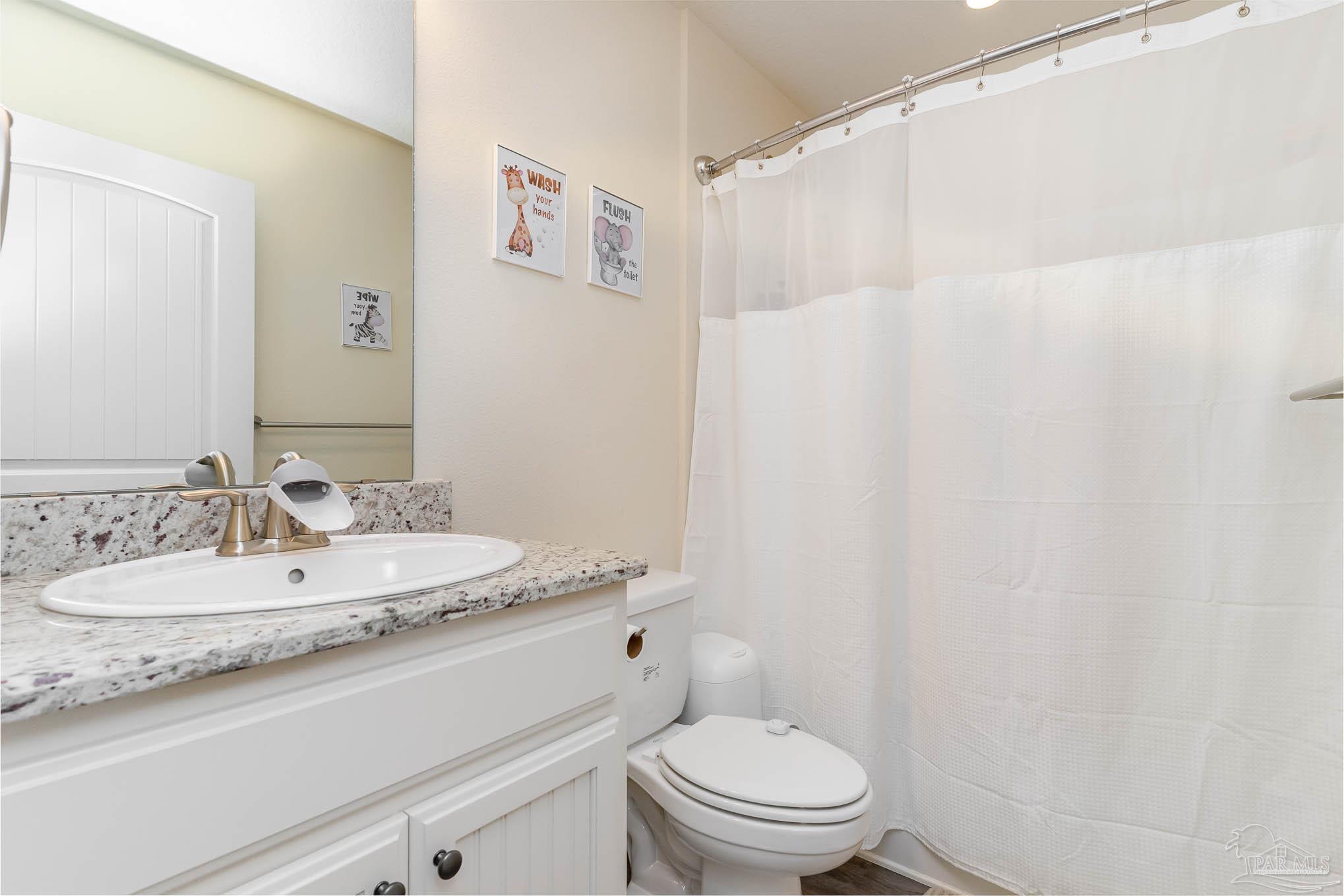 3315 Doyle Hawkins Road Navarre, FL 32566 - Photo 26 of 33 a bathroom with a granite countertop sink a toilet and a mirror