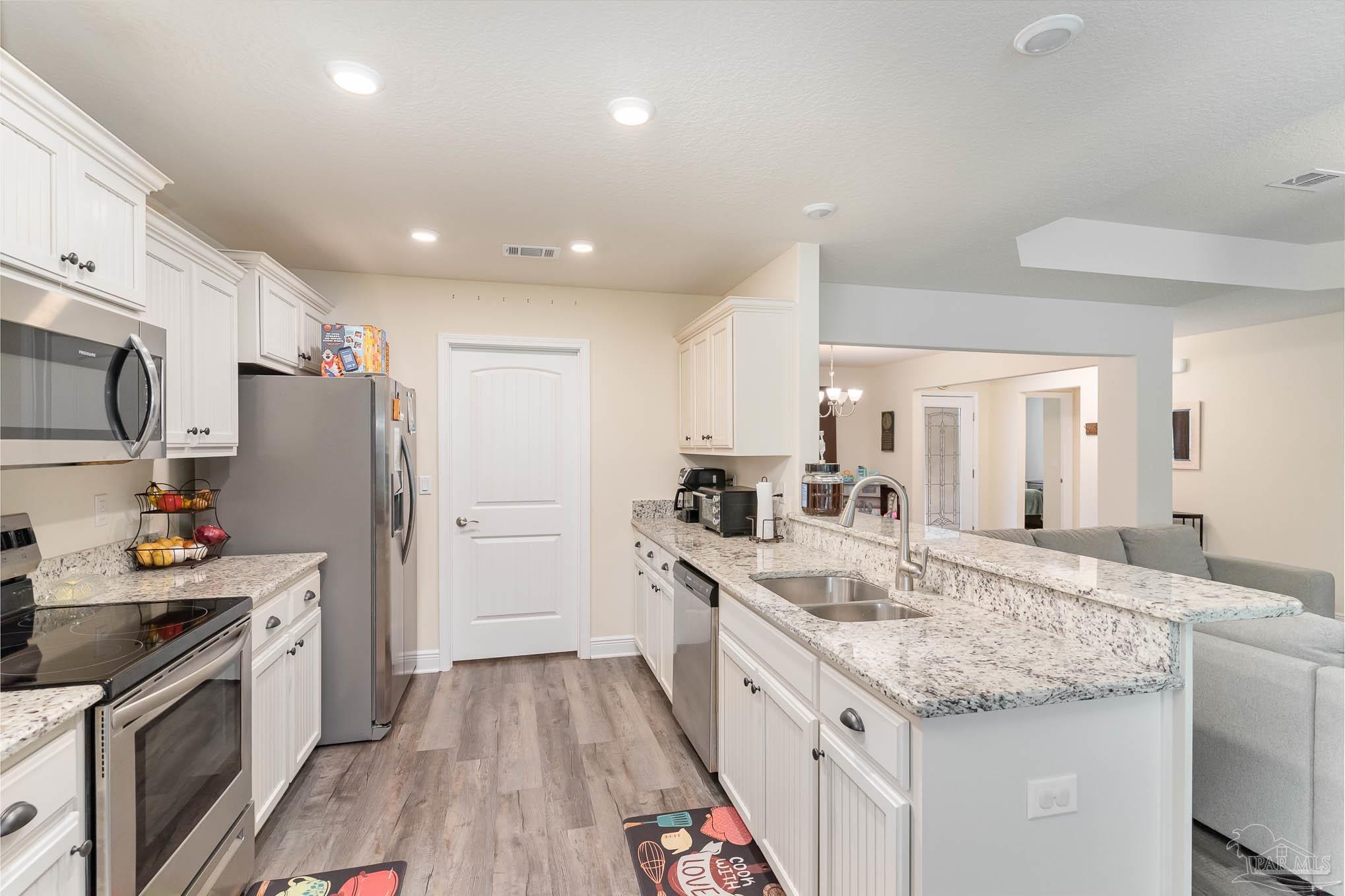 3315 Doyle Hawkins Road Navarre, FL 32566 - Photo 9 of 33 a kitchen with granite countertop a sink stove and refrigerator