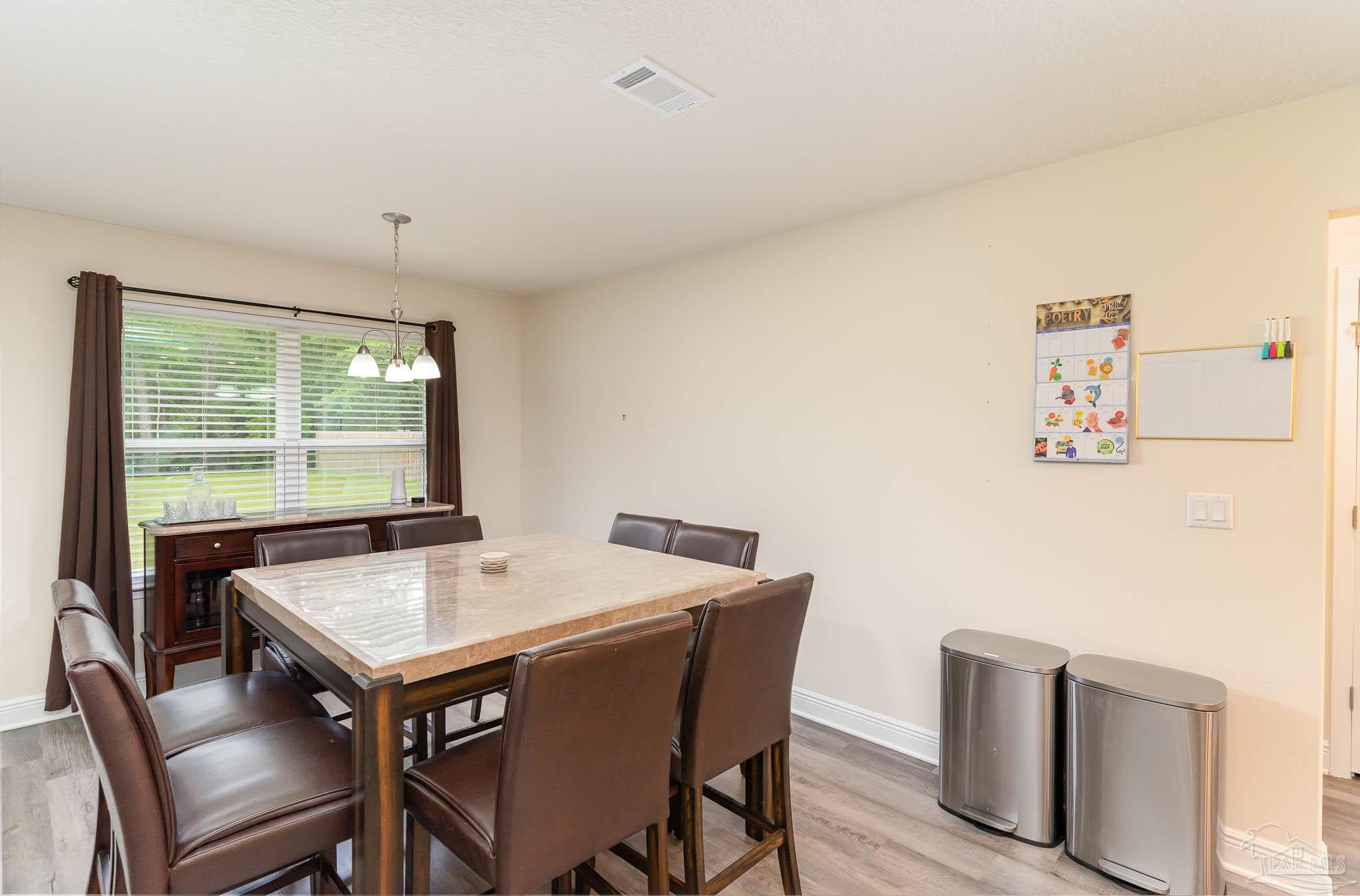3315 Doyle Hawkins Road Navarre, FL 32566 - Photo 10 of 33 a view of a dining room with furniture and wooden floor