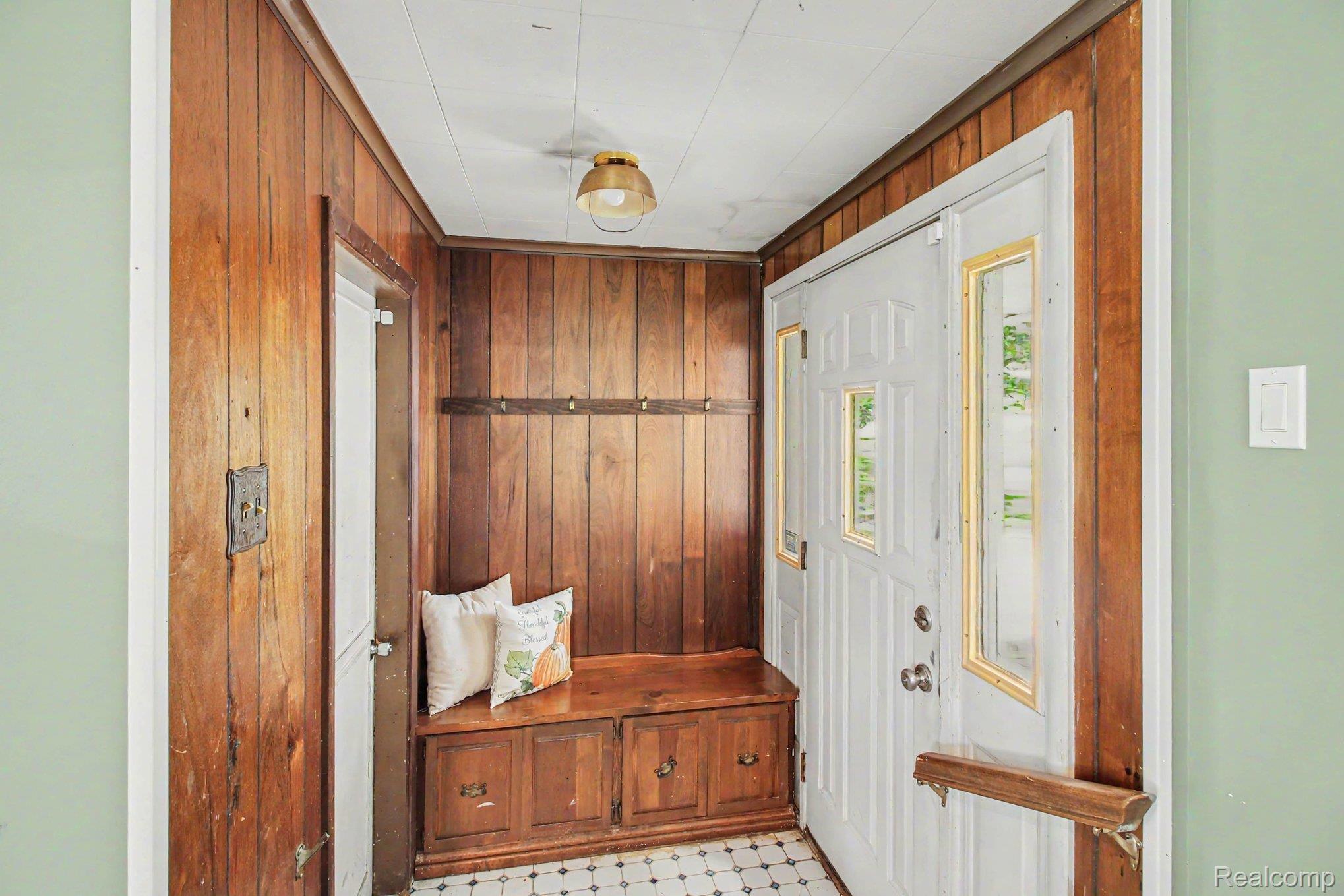 207 Elms Road Flushing, MI 48433 - Photo 16 of 30 Wood paneling accents, built-in storage bench, and a coat rack.