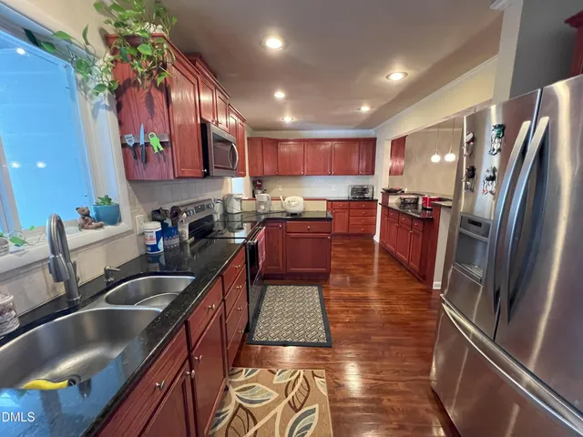 a kitchen with stainless steel appliances granite countertop a sink a stove and a refrigerator