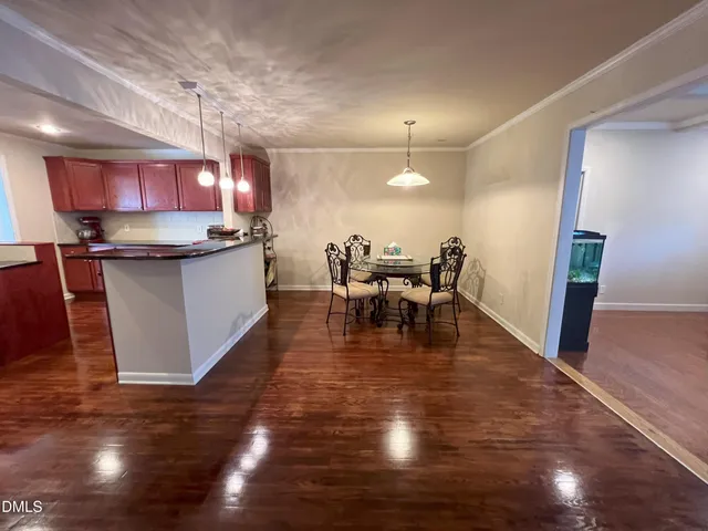 a kitchen with stainless steel appliances granite countertop a stove top oven a sink a dining table and chairs with wooden floor