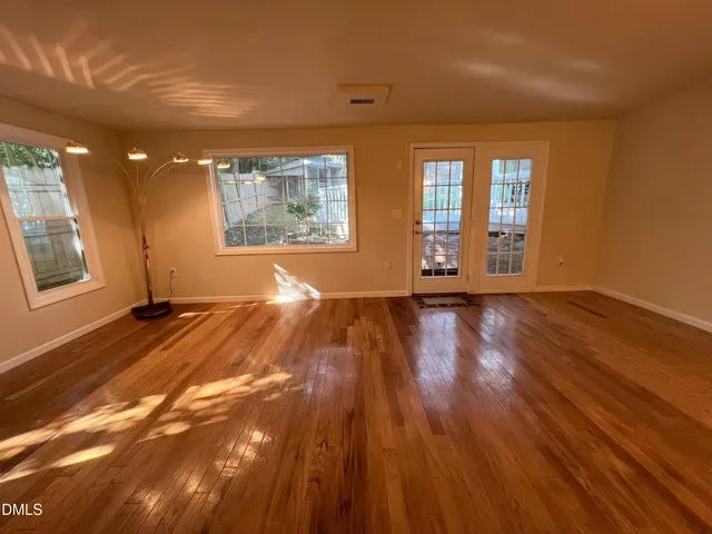a view of an empty room with wooden floor and a window